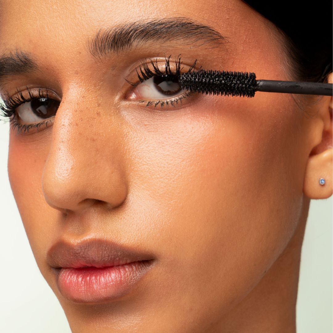 Model applying Horse Lashes (volumizing) mascara black from the base of the lashes upward for length and definition