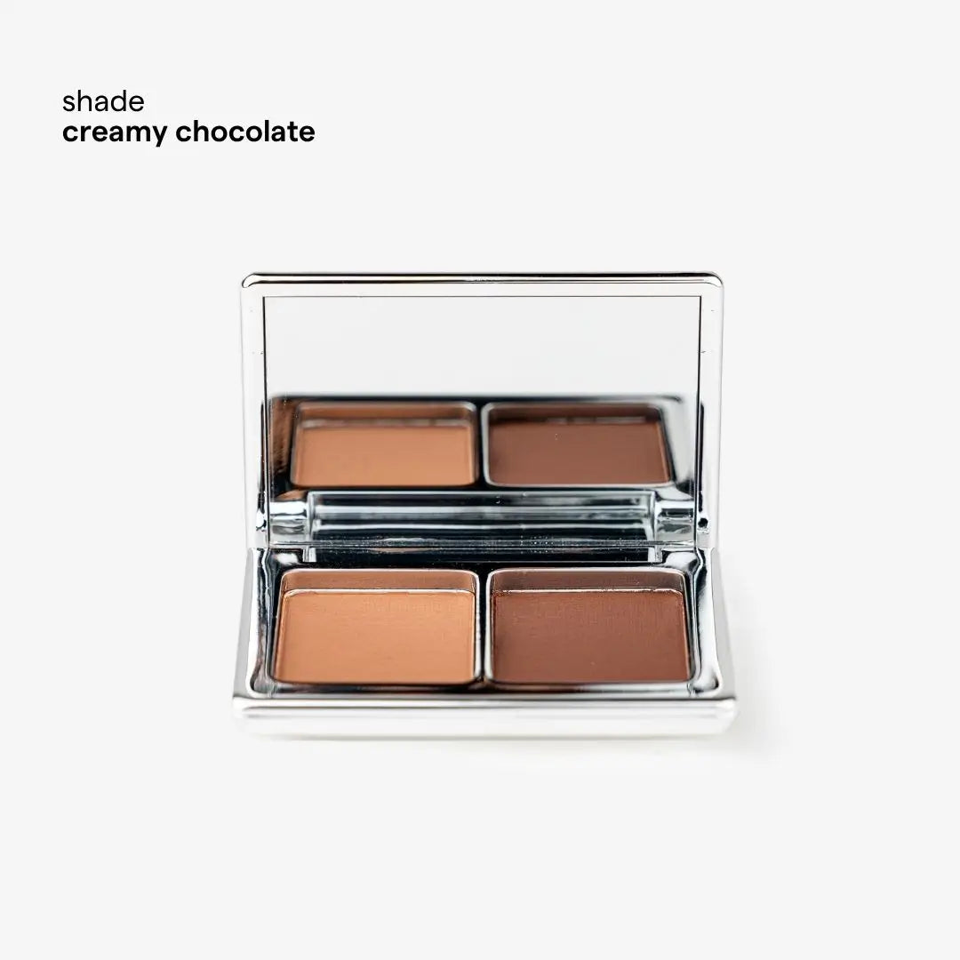 An open four-pan makeup palette in a reflective silver compact, showing four warm brown and tan shades. The text 'tono creamy chocolate' appears in the upper left on a clean white background. 