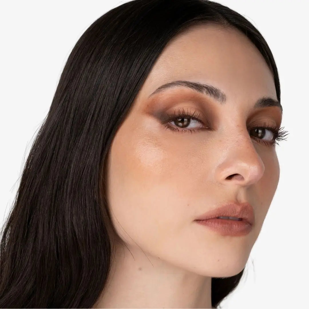 Close-up of a woman with long dark hair and warm brown eyeshadow, shown against a plain light background. Creamy Chocolate