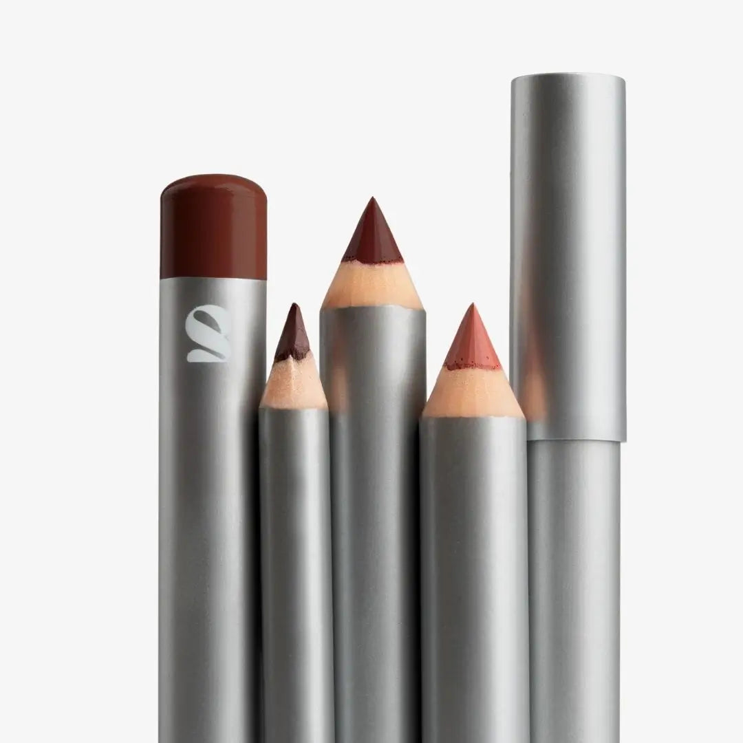Four silver cosmetic pencils and one cap shown on a clean white background, with visible shades of brown and muted pink-red. Shade chocolate