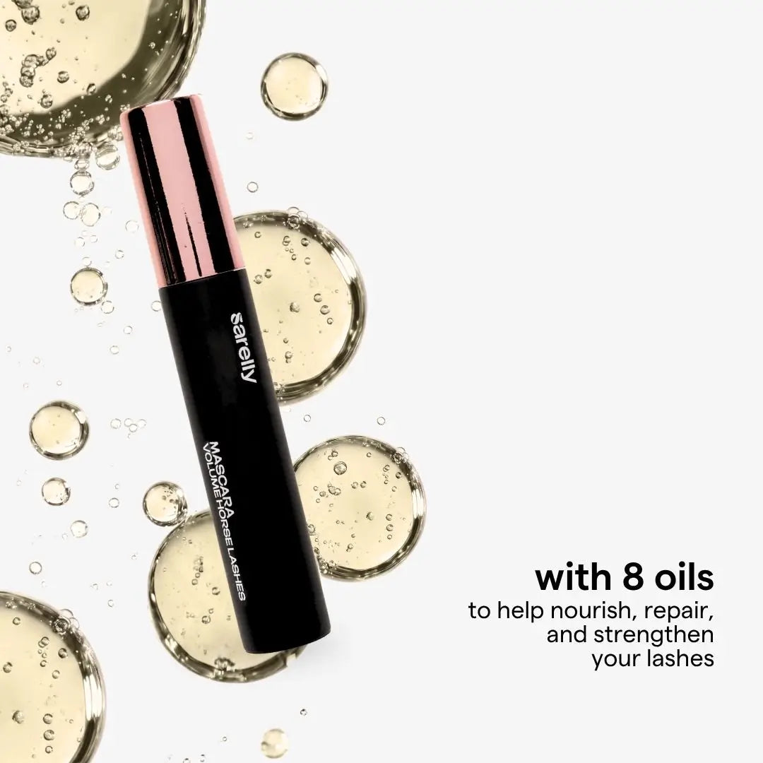 A horse lashes mascara black tube with a metallic rose gold cap, surrounded by clear oil droplets and bubbles on a white background