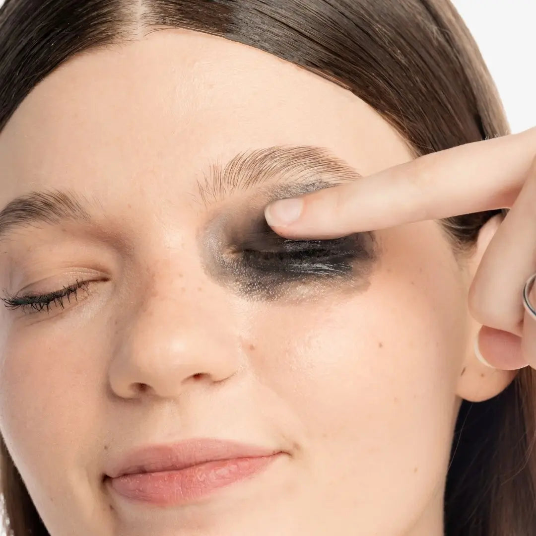 Close-up of a person applying lavadero makeup remover with their finger over one closed eye.