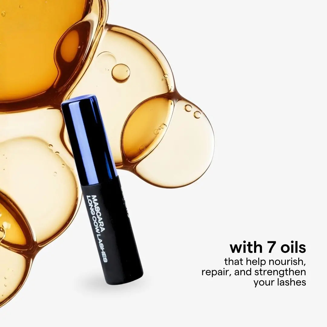 A black and blue tube of mascara cow  Lashes is shown against a white background with decorative golden oil droplets and text that reads 'with 7 oils that help nourish, repair, and strengthen your lashes'.