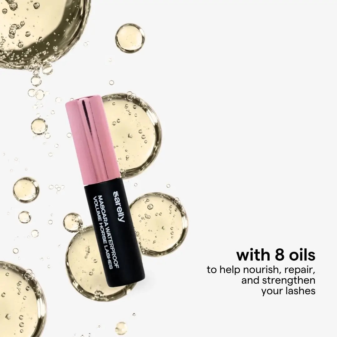 A horse lashes mascara black tube with a metallic rose gold cap, surrounded by clear oil droplets and bubbles on a white background